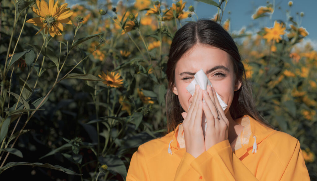 Beautiful sexy young woman lies on flowers background. Young woman got nose allergy, flu sneezing nose. Pretty woman got flu sneezing nose. Flu.